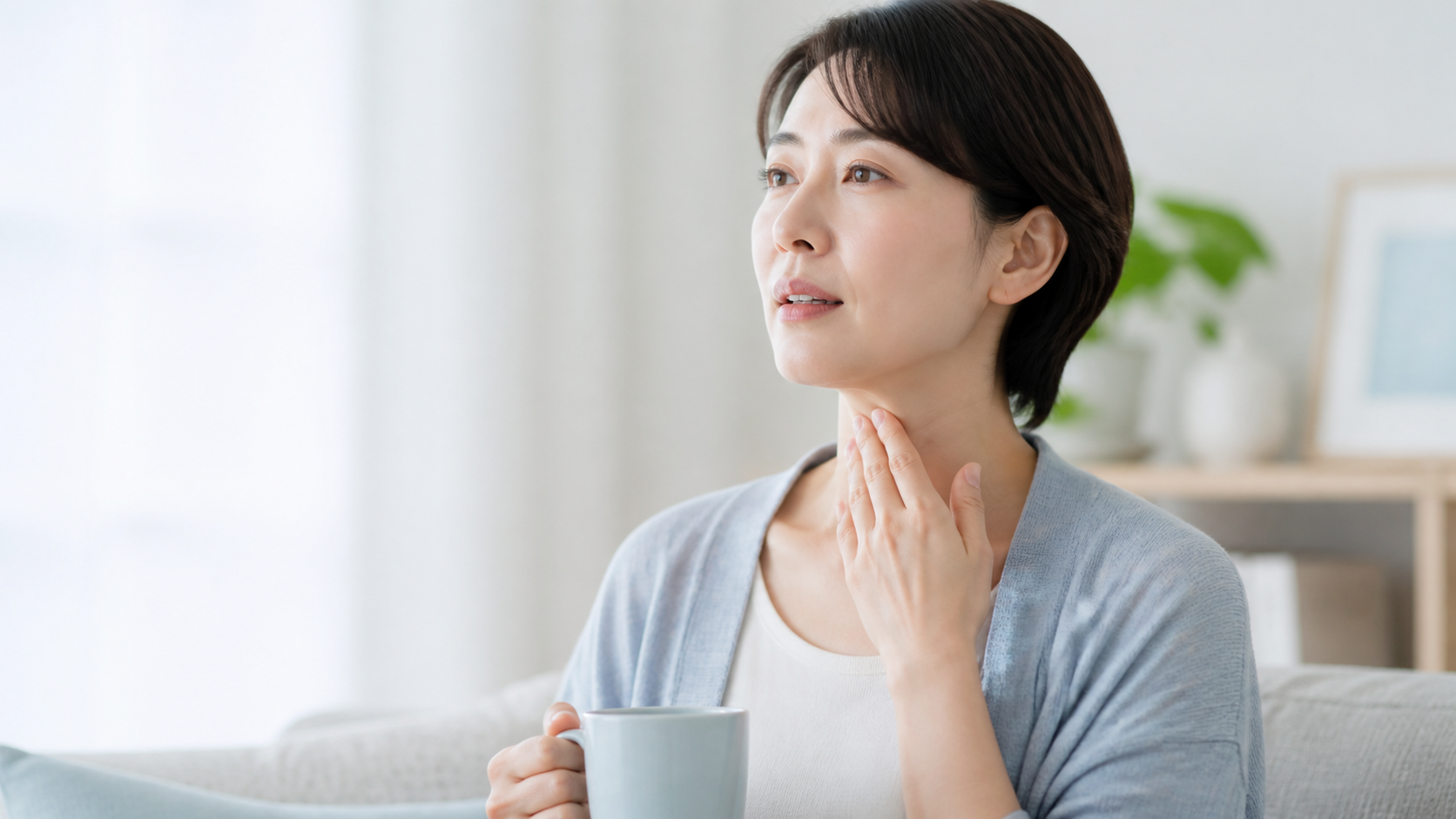 声のかすれを気にして喉に手を添える女性